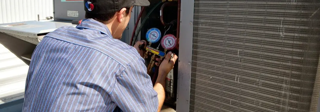 HVAC technician servicing a condenser unit in Otsego